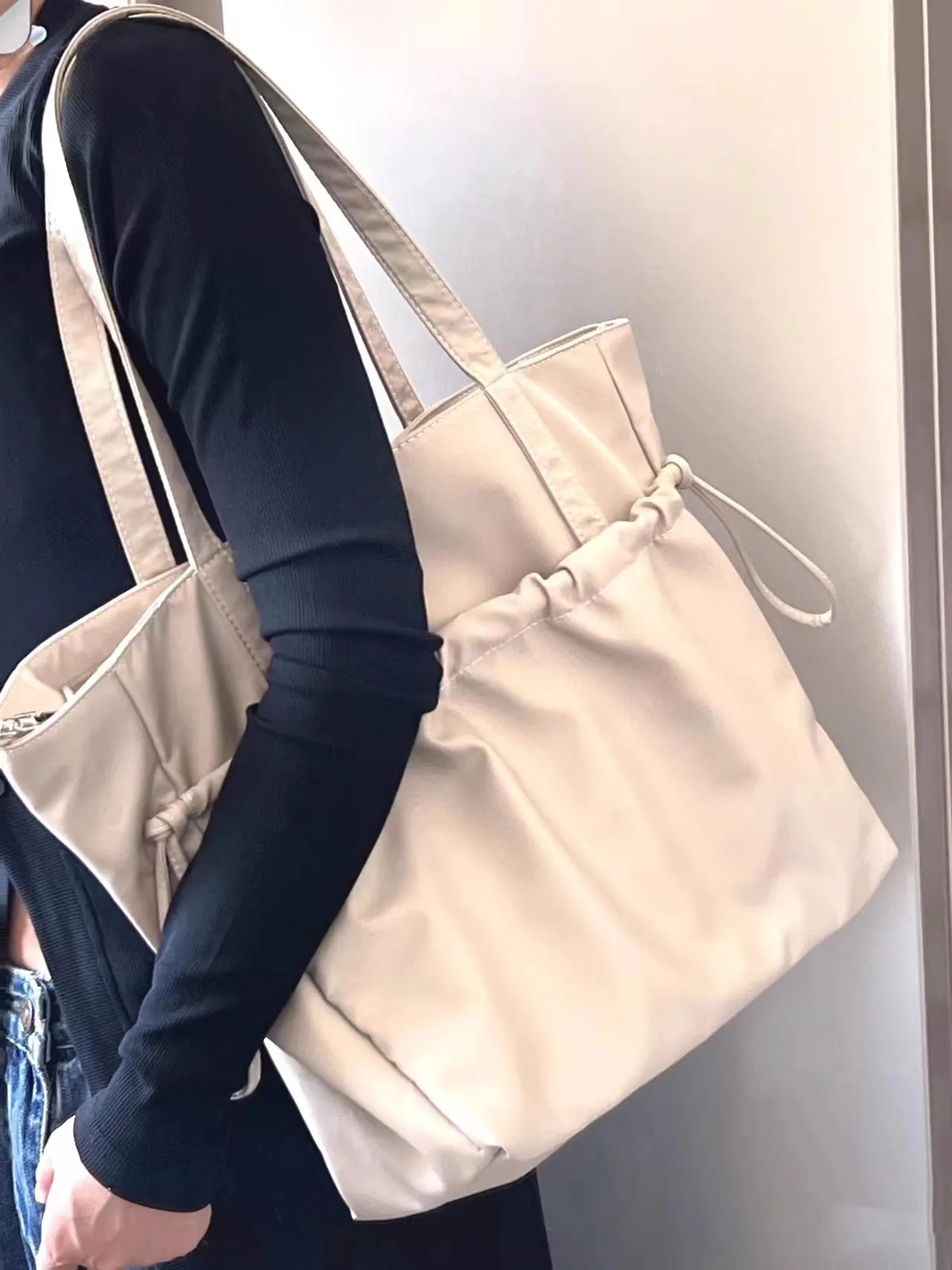 Cream tote worn over the shoulder, no face shown