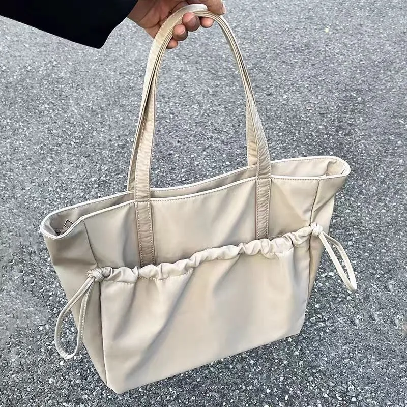 Cream nylon tote held by its two handles