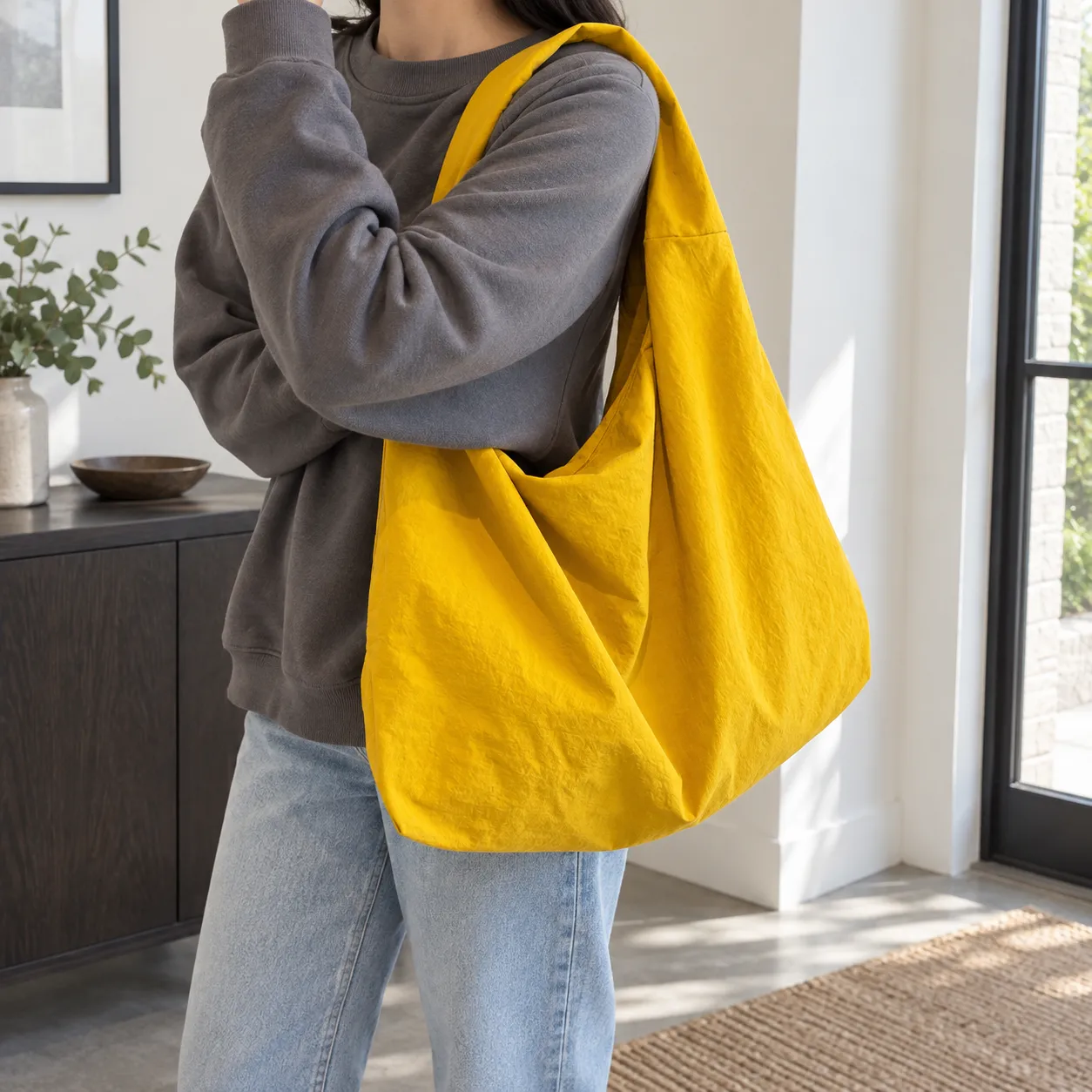 Yellow soft fabric shoulder tote carried over a grey sweatshirt. Complete handle support and bag body are visible; clothing is not included.